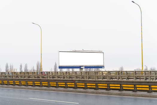 A massive billboard with a white background is prominently placed on the side of a highway, catching the attention of passing motorists.