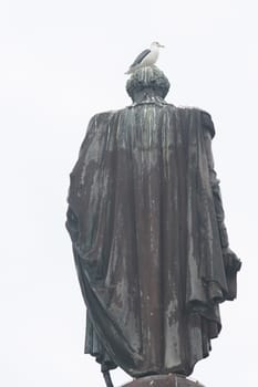 A seagull sits on the head of a statue. Vertical shot