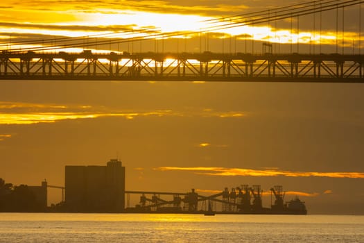 Loading industrial cranes in the distance in a bright yellow sunset - industrial cityscape. Mid shot