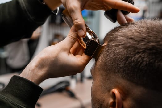 Barber uses an electrical trimmer to shave the clients hair in the sleek, contemporary barbershop