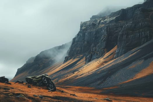 Landscape of majestic mountain in iceland with vibrant orange grass and dramatic clouds in background
