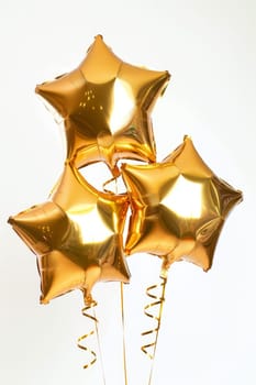 A bunch of shiny golden star-shaped balloons with festive ribbons on a white background