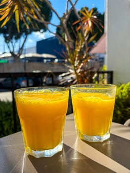 Two glasses of fresh orange juice on a table, Zumo fresco de Naranja . High quality photo