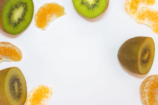 Flatlay from some peaces of yellow and green kiwi's and peaces of tangerine. On a white background.