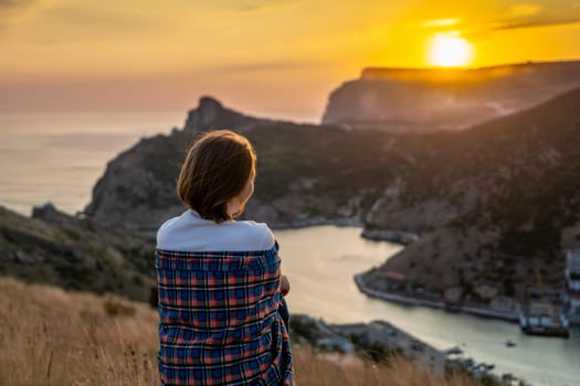 Happy woman on sunset in mountains. Woman siting with her back on the sunset in nature in summer. Silhouette