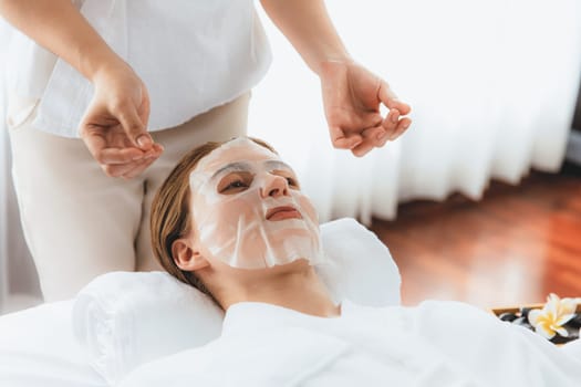 Serene modern daylight ambiance of spa salon, woman customer indulges in rejuvenating with facial skincare mask. Facial skin treatment and beauty cosmetology procedure for face. Quiescent