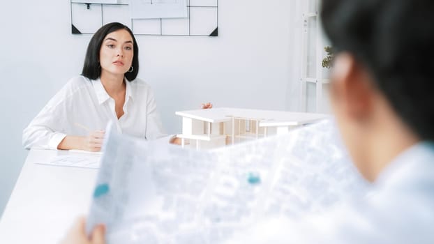 Professional asian male project manager hand puts the map on meeting table while discuss and brainstorm with coworker about building project at meeting room with blueprint hand behind. Immaculate.