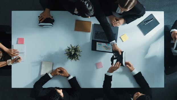 Top view of smart manager give vr head set to businesspeople while businesswoman prepare data analysis or analytic graph in laptop at meeting. Startup team preparing to enter meta verse. Directorate.