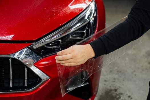 The process of applying protective vinyl film to car headlights in detailing