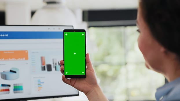 Worker checking greenscreen display on smartphone, holding device with copyspace blank software in coworking space. Woman working with isolated mockup display in agency office. Close up.