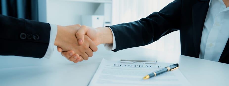 Two business executive shake hand in boardroom, sealing agreement merging two company. Handshake symbolize business partnership and cooperation. Corporate acquisition and merger concept. Shrewd