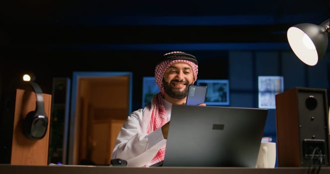 Arabic man checking up on abroad living friend during video conference meeting over the internet. Muslim person enjoying time together with mate in online video call session while at home