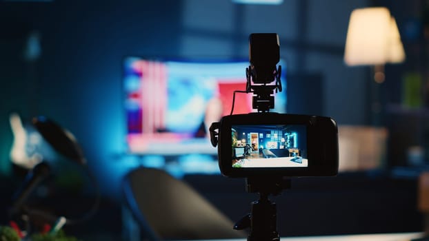 Extreme close up shot of camera on tripod used by media star in dimly lit apartment studio to film video for online platforms. Recording device in empty room used by content creator to capture footage