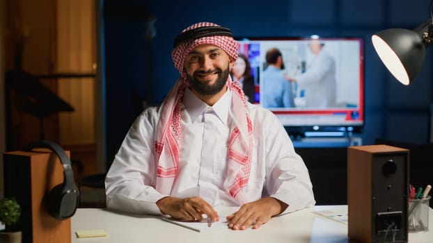 Portrait of smiling arab man engaged in elearning class video conference communication. Muslim student in online videocall greeting tutor, listening to his teachings while taking notes
