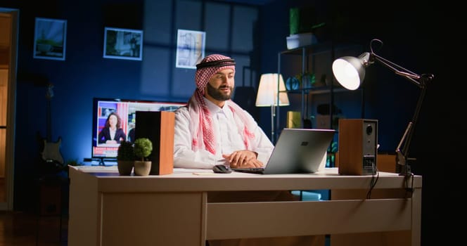 Arabic job candidate remotely being interviewed by human resources team while at home. Smiling muslim man getting his credentials checked during online video conference meeting before being employed