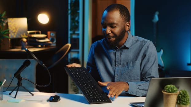 Content creator in dimly lit living room using camera to film keyboard review for online streaming platforms. Online star hosts technology internet show, unboxing peripherals