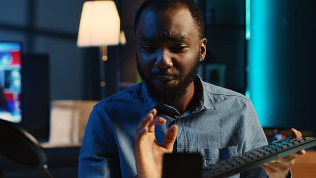 African american technology internet star filming review of newly released wireless keyboard, greeting audience and presenting them feedback about typing experience, doing endorsement