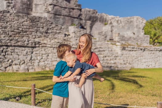 Mother and two sons tourists enjoying the view Pre-Columbian Mayan walled city of Tulum, Quintana Roo, Mexico, North America, Tulum, Mexico. El Castillo - castle the Mayan city of Tulum main temple.