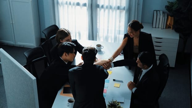 Top view of professional project manager present idea while diverse team putting hands together and clapping hand to celebrate successful strategy at meeting room. Show unity, teamwork. Directorate.