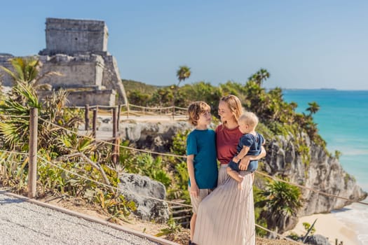 Mother and two sons tourists enjoying the view Pre-Columbian Mayan walled city of Tulum, Quintana Roo, Mexico, North America, Tulum, Mexico. El Castillo - castle the Mayan city of Tulum main temple.