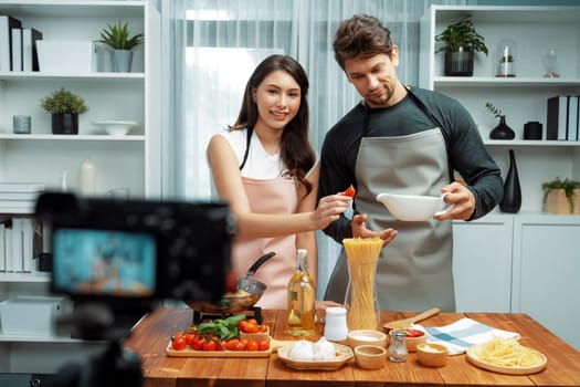 Couple chef influencers on cooking show presenting ingredient of spaghetti, meat, chilli, tomato, garlic and seasoning sauce's homemade special recipe recording on camera on live channel. Postulate.