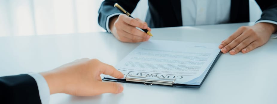 Business executive signing contract agreement document on the bale with the help from company attorney or lawyer service in law firm office. Business investing and finalizing legal processing. Shrewd