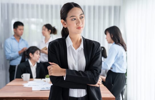 Portrait of happy young asian businesswoman looking at camera with motion blur background of business people movement in dynamic business meeting. Habiliment