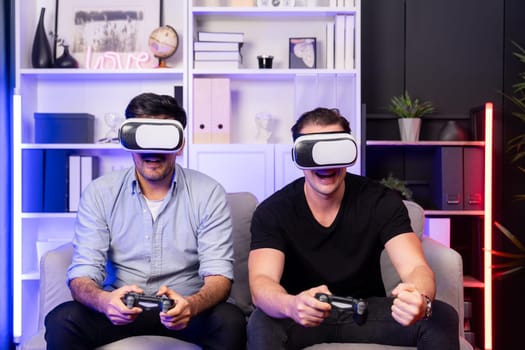 Buddy friend gamers playing video game using joysticks and VR headset of virtual technology in reality in studio room with neon blue light. Comfy living indoor with cheerful fighting winner. Sellable.