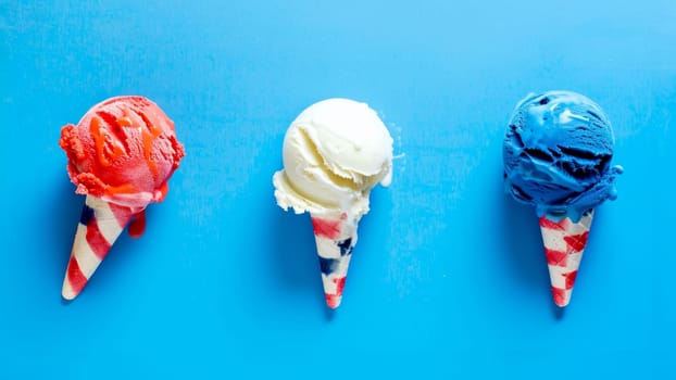 Red, white, and blue ice cream cones with American flag-themed wrappers on blue surface.