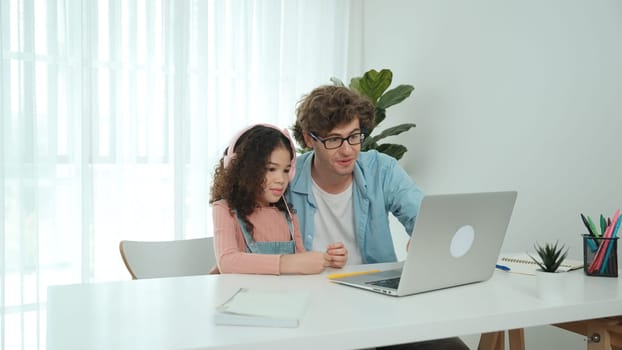 Caucasian dad put headphones on daughter while girl learning code. Father take care schoolgirl while teaching writing engineering prompt and generate Ai by using laptop. Online learning. Pedagogy.