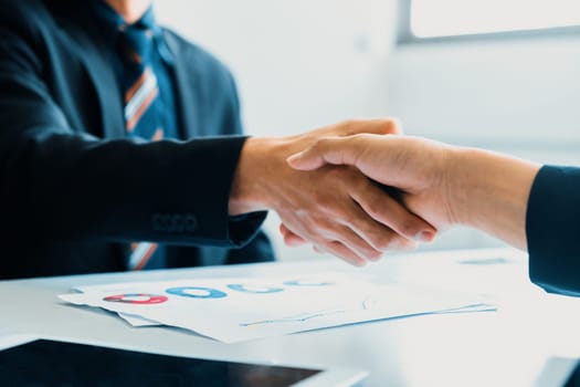 Business people agreement concept. Businessman and Asian businesswoman do handshake in the office. uds