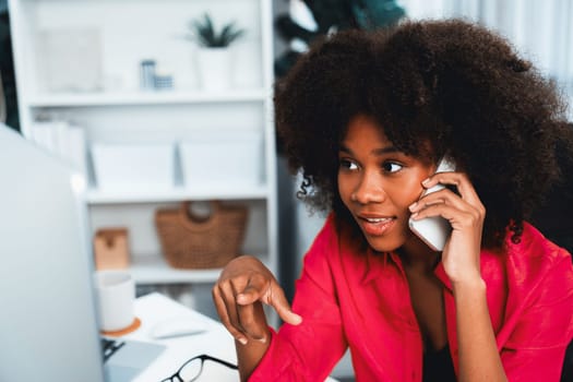 African woman talking with coworker or friend on the phone and looking at the screen with happy face. Achievement for promoting job position in the company with the good news life. Tastemaker.