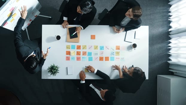 Top down aerial view of manager standing and present marketing plan to skilled investor. Diverse business team working together to analyze financial statistic graph at meeting table. Directorate.