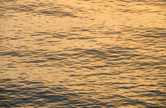 Mediterranean sea waves of golden color at sunset. water background