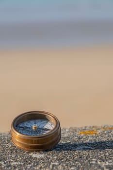 Compass on stone ledge overlooking ocean sand and sky in bakground. Background image. concept of finding direction in life. Verticle selective focus. High quality photo