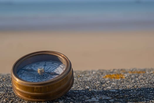 Compass on stone ledge overlooking ocean sand and sky in bakground. Background image. concept of finding direction in life. Horizontal selective focus. High quality photo