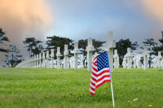 American cemetery at Normandy area. WWII memorial. Lines of grave stones with american flag. moring glow in blue sky and clouds. High quality photo