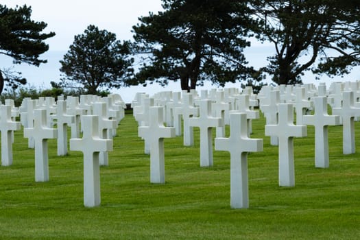 American cemetery at Normandy area. WWII memorial. At a distance white marble grave stones on green grass. High quality photo