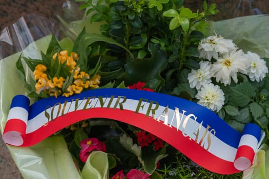 Flower wreath and ribbon at American cemetery monument at Normandy area. WWII memorial. Lines of grave stones with american flag. High quality photo