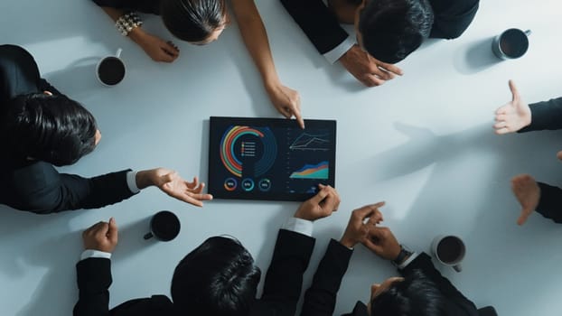 Top down aerial view of professional businessman analyze stock market chart with tablet with investment graph placed at table while investor group pointing at tablet. Creative business. Directorate.