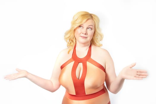 A cheerful, plump middle aged woman confidently poses in a red swimsuit or underwear, promoting the body positivity movement in a bright studio settings