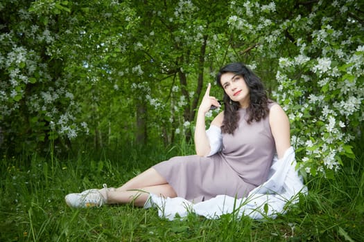 Joyous brunette woman near Blossoms of apple tree in a Spring Garden outdoors. The Concept of face and body care. The scent of perfume and tenderness