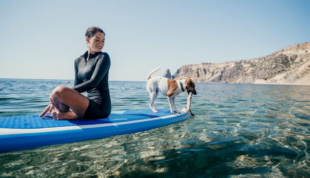 Sea woman sup. A happy positive woman in hat with family relaxing in sea, aerial back view of family on SUP board floating on calm water. Active lifestyle at sea. Summer vacation. Slow motion