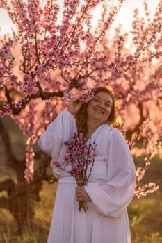 Woman blooming peach orchard. Against the backdrop of a picturesque peach orchard, a woman in a long white dress enjoys a peaceful walk in the park, surrounded by the beauty of nature