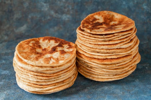 Flatbread lavash, chapati, naan, heap of tortilla on a blue background Homemade flatbread stacked