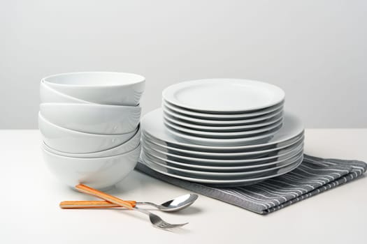 Stylish table setting with white dishware on white tablecloth close up