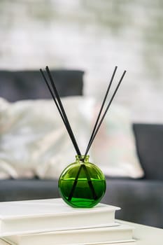 Aroma diffuser bottle with sticks in living room, close up