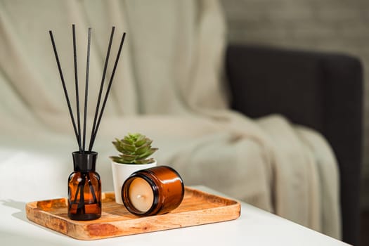 Aromatic reed freshener and candle on table in room close up