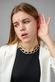 Woman in White Jacket Listening With Hand to Ear close up