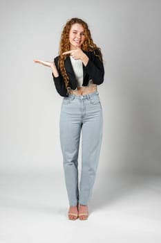 Smiling Young Woman Pointing While Posing in a Studio close up